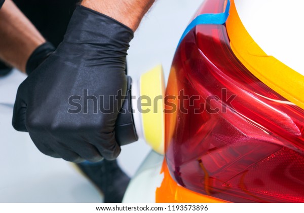 Car polish wax worker\
hands holding polisher and polish. Close up at hand holding car\
polisher. Man holds a polisher in the hand and polishes the car.\
Car detailing