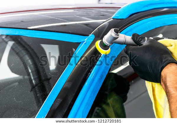 Car polish wax worker hands\
applying protective tape before polishing. Buffing and polishing\
car. Car detailing. Man holds a polisher in the hand and polishes\
the car