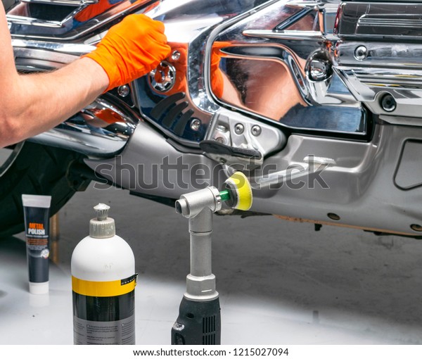 Car polish wax worker hands applying protective\
tape before polishing. Buffing and polishing motorcycle. Car\
detailing. Man holds a polisher in the hand and polishes the\
motorcycle. Polishing tools
