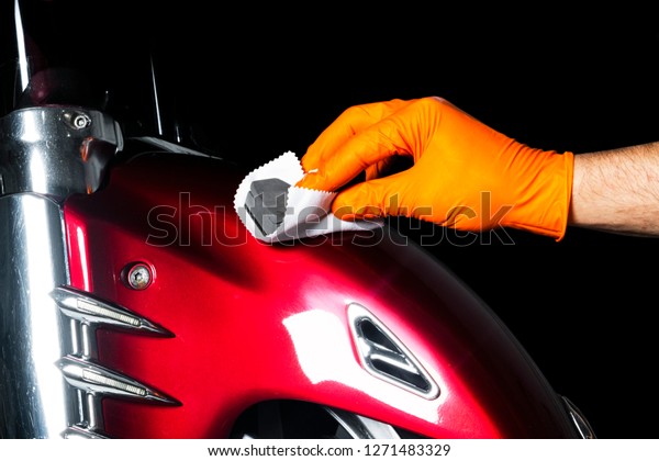 Car\
polish wax worker hands polishing motorcycle. Buffing and polishing\
vehicle with ceramic. Car detailing. Man holds a polisher in the\
hand and polishes the motorcycle with nano\
ceramic.