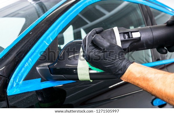 Car\
polish wax worker hands applying protective tape before polishing.\
Buffing and polishing car. Car detailing. Man holds a polisher in\
the hand and polishes the car. Tools for\
polishing