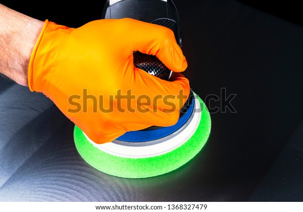 Car polish wax\
worker hands polishing vehicle. Buffing and polishing car. Car\
detailing. Man holds a polisher in the hand isolated on black\
background. Tools for\
polishing