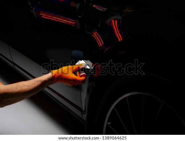 Car polish wax worker hands polishing car.\
Buffing and polishing vehicle with ceramic. Car detailing. Man\
holds a polisher in the hand and polishes the car with nano\
ceramic. Tools for\
polishing