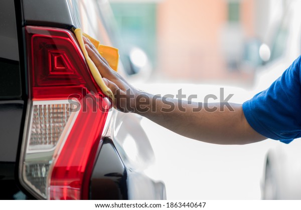 The car polisher uses a microfiber cloth and polish\
to wipe the car\'s tail lights to make them shine He takes care of\
every detail of the car.