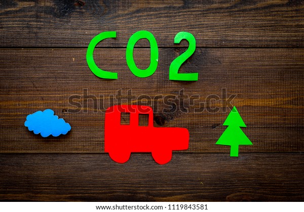 Car pollutes the environment by carbon dioxide.\
Car, environment and CO2 cutout on dark wooden background top view\
copy space
