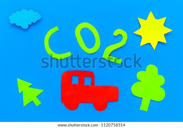 Car pollutes the\
environment by carbon dioxide. Car, environment and CO2 cutout on\
blue background top view