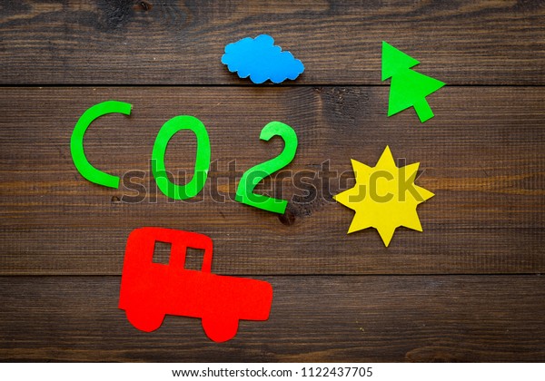 Car pollutes the environment by carbon dioxide.\
Car, environment and CO2 cutout on dark wooden background top view\
copy space