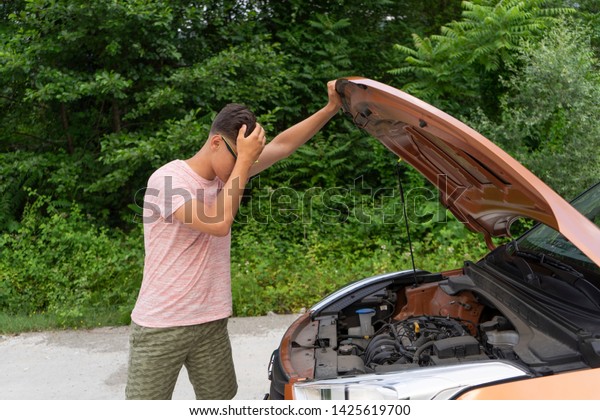 Car problems. Novice driver opens the hood,
looking inside. Car-care
concept