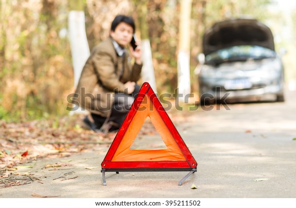 Car with problems and a red triangle to warn other\
road users