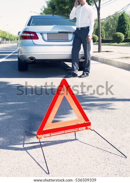 Car with problems and a red triangle to warn other\
road users