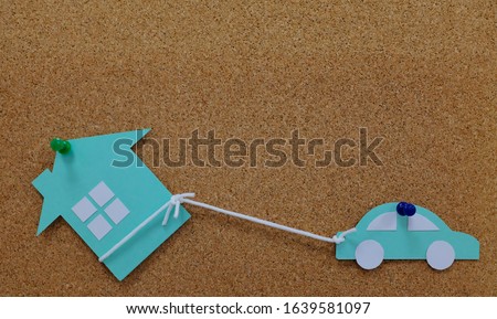 Car pulling a house model paper cutout. House as collateral property for auto loan