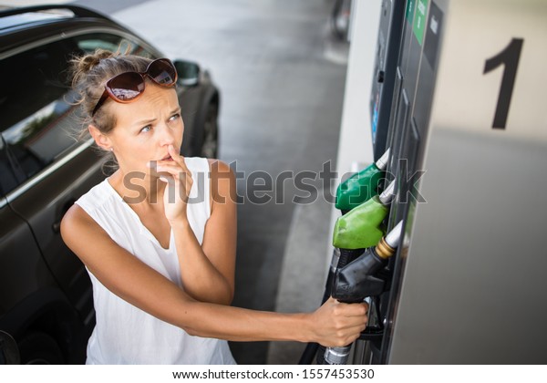 Car pumping gas at gas pump. Closeup\
of man pumping gasoline fuel in car at gas\
station.