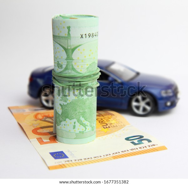 Car purchase or the tax on\
the car concept.  Euro banknotes  and toy blue car. White\
background.\
