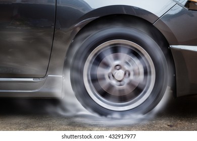 Car racing spinning wheel burns rubber on floor.