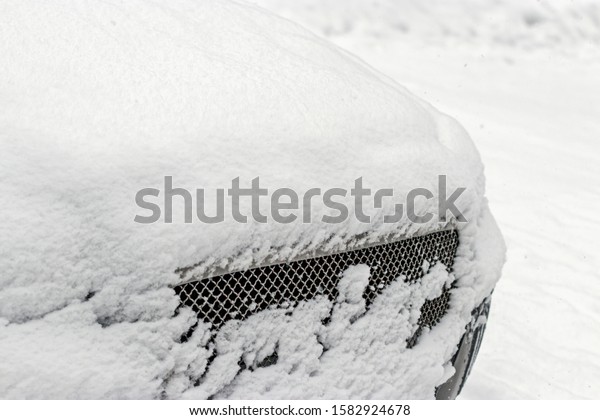 The\
car radiator grill is covered in snow in the courtyard of a\
residential area of the city. Winter day in\
Siberia.