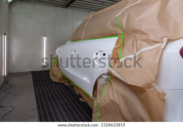 The car rear view after the accident in the camera\
for car body repair is partially covered with paper and pasted over\
with green masking tape for painting the side doors and the fender\
with white