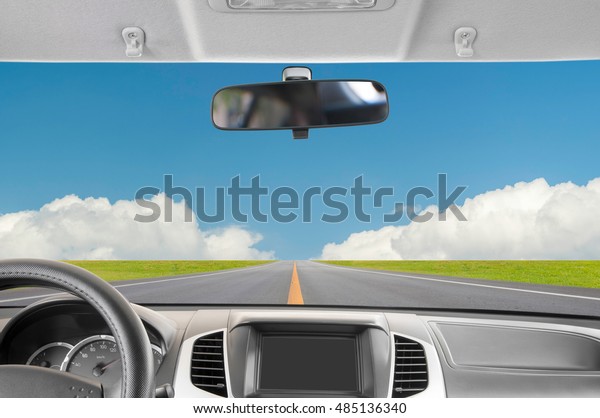 Car rear view mirror inside the car and\
drive a car on road with blue sky\
background.