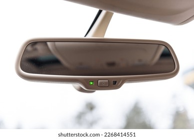 Car rearview mirror in automobile. Vehicle interior with rear view mirror and windshield - car salon concept. Auto dim button. Auto dimming button. Details interior closeup.