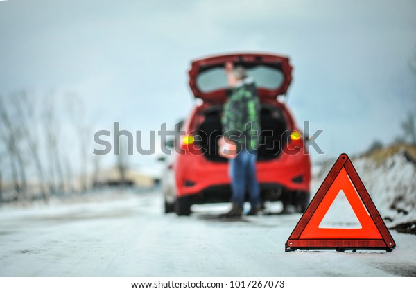 Car red\
triangle in winter. Emergency sign. Broken car on highway. Warning\
triangle on snow after car\
breakdown.