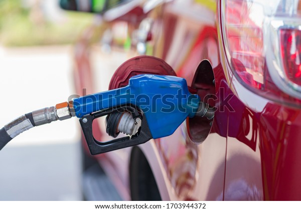 Car refueling on the petrol station with pumping\
gasoline fuel in car, diesel or gasoline being pumped into a motor\
vehicle car.