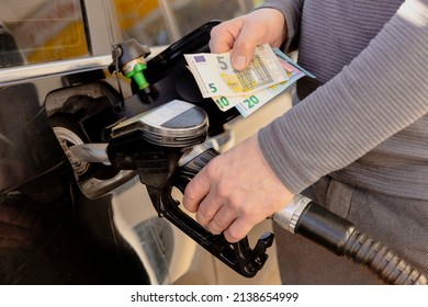 Car refuelling on petrol station. Man refilling car with fuel and holding money, euros. Close up. Gasoline, diesel is getting more expensive. Petrol industry and service. Petrol price and oil crisis.