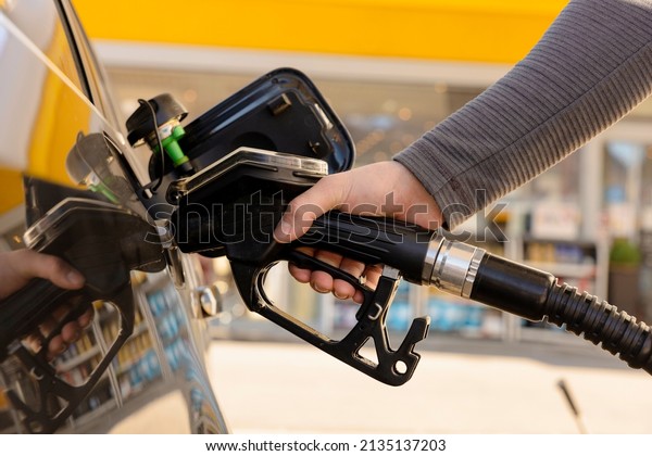 Car refuelling on the petrol station. Man\
refilling the car with fuel. Close up view. Gasoline, diesel is\
getting more expensive. Petrol industry and service. Petrol price\
and oil crisis concept.