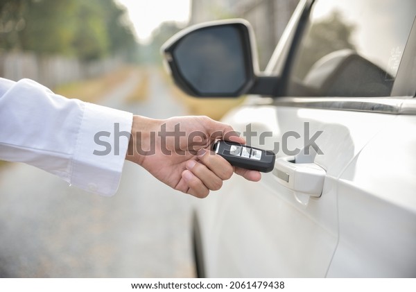 Car remote control by smart key, Hand\
holding smart key to lock doors of white\
car
