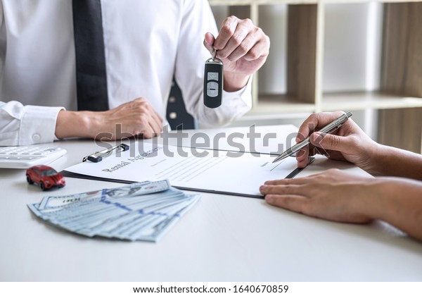 Car rent agent manager sending key of new car\
giving to woman client after signing good deal agreement contract,\
renting considering\
vehicle.