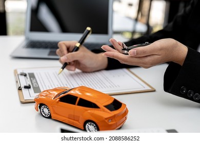 Car rental company employees are checking the contract before sending the car to the customer to rent the car, preparing the contract for the customer to sign the rental agreement. Car rental concept. - Shutterstock ID 2088586252