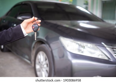 Car Rental Driver.hand Woman Holding Car Keys On Blur Image Of Black Car. For Buying Or Selling A Car. Business Or Finance Concept.