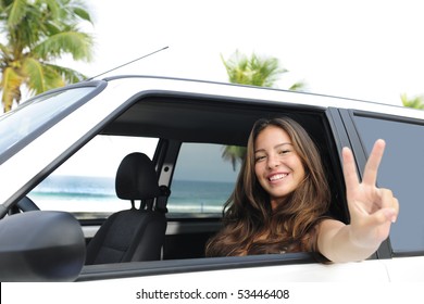 Car Rental: Happy Woman In Her Car Near The Beach Showing Victory Sign