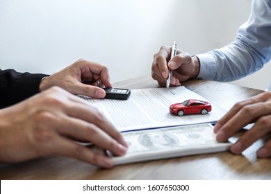 Car rental and Insurance concept, Young salesman receiving money and giving car's key to customer after sign agreement contract with approved good deal for rent or purchase.
