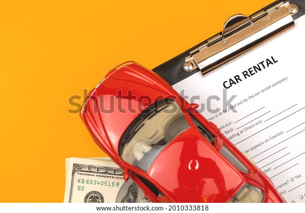 Car rental lease contract form. Office\
desk with clipboard and toy car. Copy space\
photo