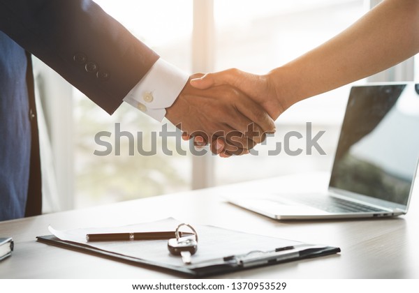 Car rental\
service concept. Close up view Hand of agent giving car key to\
customer after signed rental contract\
form.