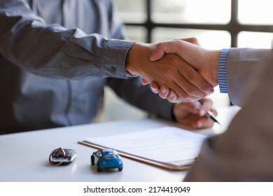 Car Rental Service Sales Give The Car Key Concept. Close Up View Hand Of Agent Handshake To The Customer After Signing Rental Contract Form.