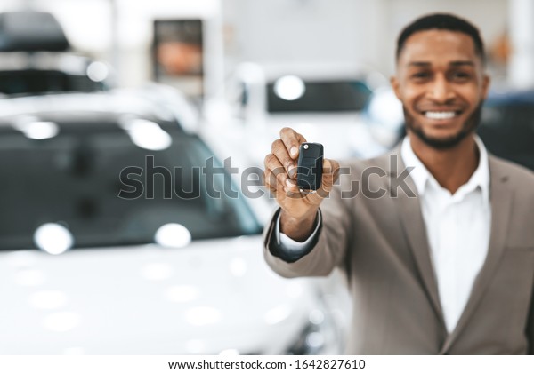 Car\
Rental. Unrecognizalble Agent Showing Auto Key Standing In\
Automobile Rental Office. Empty Space, Shallow\
Depth