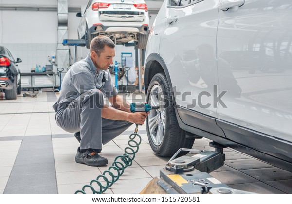 car repair, BMW advertising, Moscow,\
1.11.2018: car repair: wheel replacement closeup. mechanic screwing\
or unscrewing car wheel at car service\
garage
