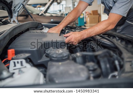 Car repair and cleaning concept - car engine close-up, wiping parts under the hood