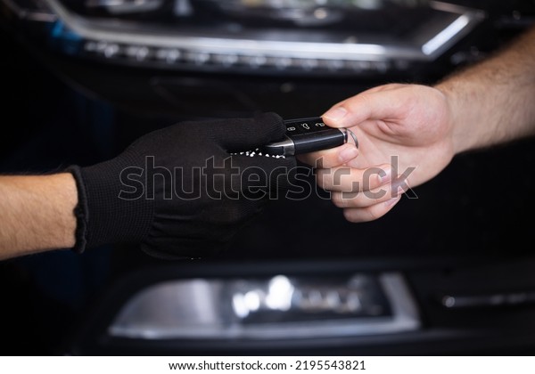 Car repair. Man\
owner of the auto gives the keys to the car repairman. Vehicle\
breaks down. Close up shot of hands of male client giving car key\
to mechanic in auto repair\
shop