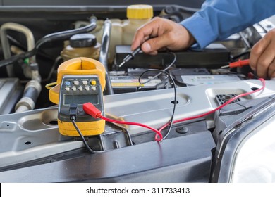 Car Repair Service, Auto Mechanic Checking A Car Battery Level By Voltmeter