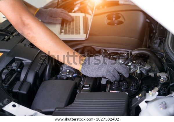 Car repair service, Auto mechanic checking\
battery in a engine.