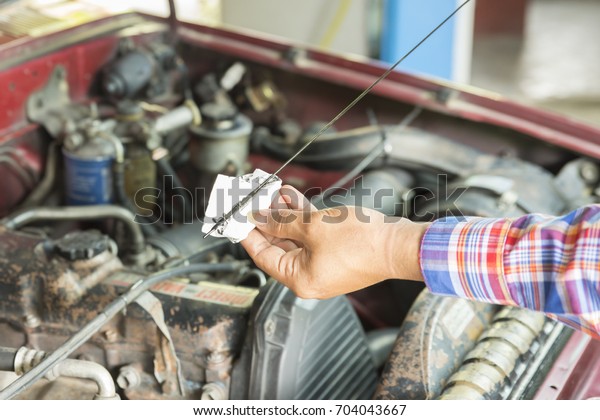 Car repair service, Auto mechanic checking oil\
level in a engine