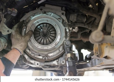 Car repair in a car service. Replacing the clutch disc of a gearbox on a car at a service station. Hands of a professional car mechanic. Cars repair technology. Technical photography. - Shutterstock ID 1744143626