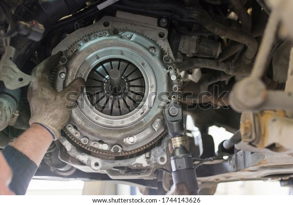 Car repair\
in a car service. Replacing the clutch disc of a gearbox on a car\
at a service station. Hands of a professional car mechanic. Cars\
repair technology. Technical\
photography.