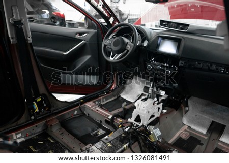 Car repair and service station. Automobile disassembly. Warranty. Vehicle interior. Wires stick out from the dashboard. Wheel and airbag.