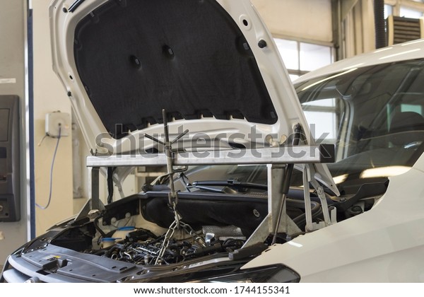 Car repair\
at a service station. A special tool is installed on the car for\
repair. The engine compartment of the\
car.