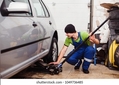 car repair at a service station. A young man lifts a car with a jack
