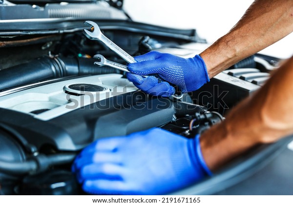 car\
repair shop concept photo. motor repairing close up. mechanic hands\
hold wrenches on the background of a car\
engine
