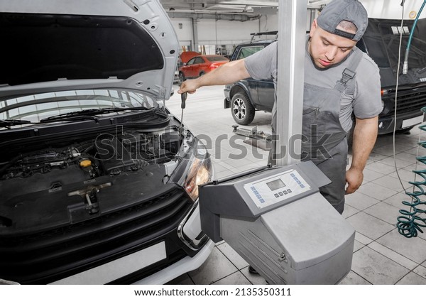 Car\
repair shop - worker checks and adjusts the headlights of a car\'s\
lighting system. Adjusting the car headlight\
light