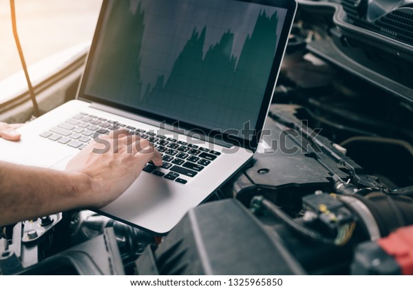 Car repair technicians use laptop computers\
to measure engine values for\
analysis.